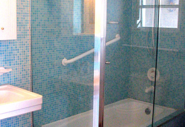 A bathroom with blue tile and glass shower door.